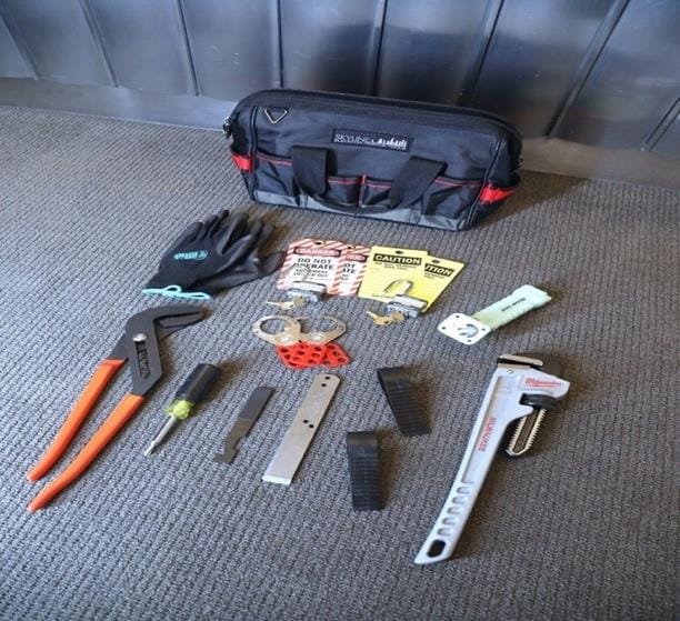 Equipment room bag contents including lockout tags, locks, pipe wrench, pliers, gloves, and access tools